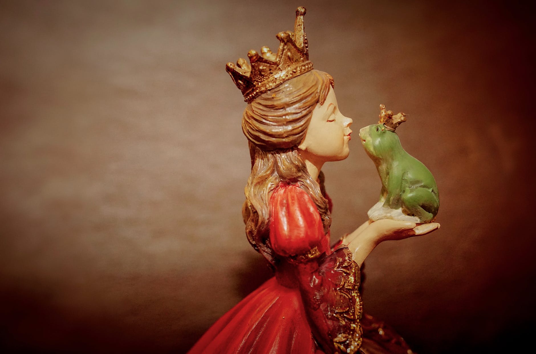 woman wearing crown holding frog figurine
